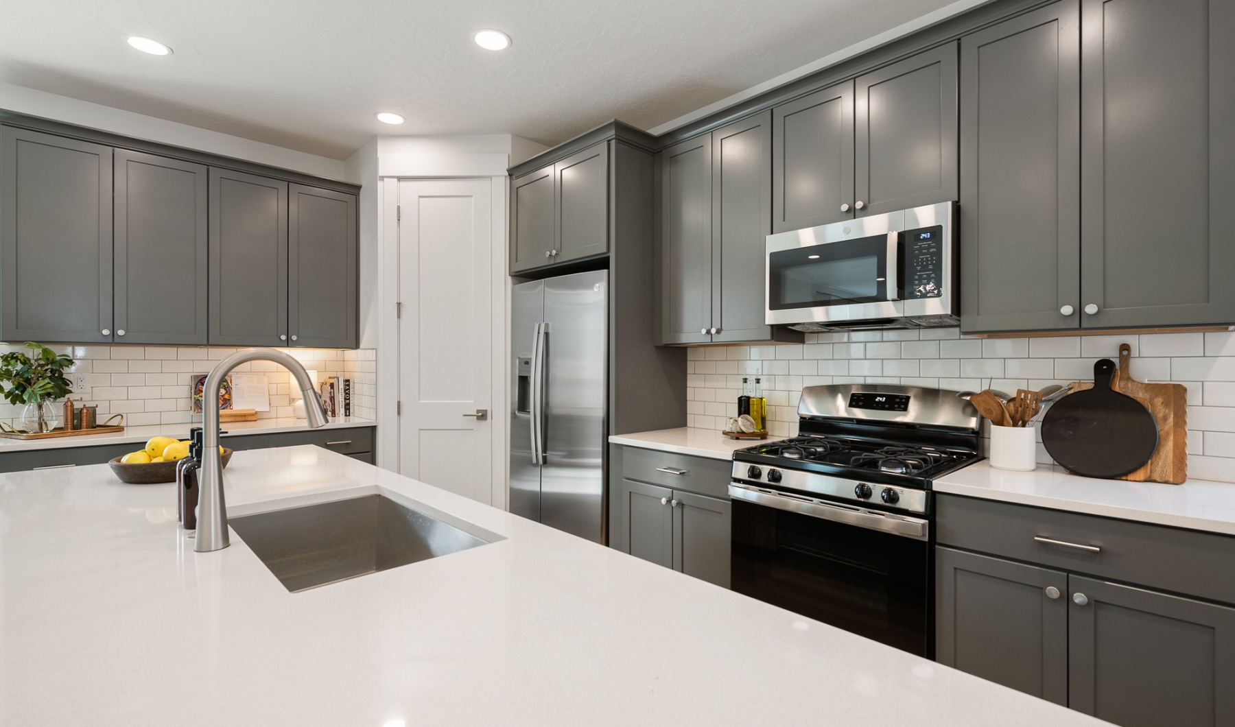 Modern kitchen with stainless steel appliances, granite countertops, goose-neck faucet, and stylish cabinets